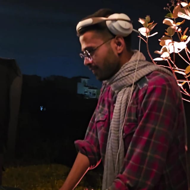 ARME at the decks at night, headphones around his neck